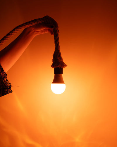 Hænder holder en lysende lampe, der hænger i et reb