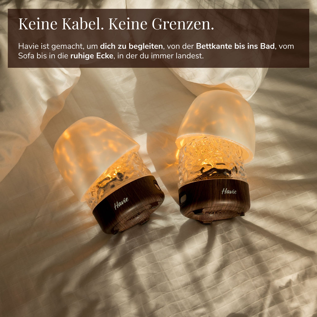 Zwei kabellose Havie-Lampen mit Akku leuchten warm auf einem Bett.