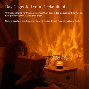 Eine Frau liest neben Havie, die ein gemütliches Schlafzimmer in warmes orangefarbenes Licht taucht.