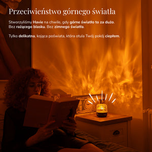 Kobieta czyta obok lampki Havie, która rzuca ciepły pomarańczowy blask na przytulną sypialnię.